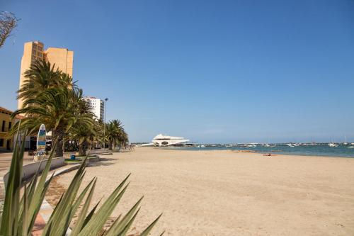 a sandy beach with palm trees and the ocean at Hotel Madrid in Santiago de la Ribera