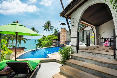 a house with a swimming pool and an umbrella at Panviman Resort Koh Phangan in Thong Nai Pan Noi
