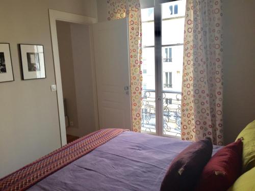 une chambre avec un lit et une grande fenêtre dans l'établissement Appartement Saint-Dominique 7 eme, à Paris
