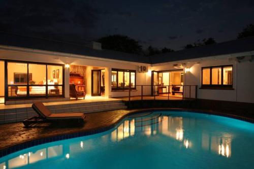 a swimming pool in front of a house at night at de Charmoy Riverside in Durban