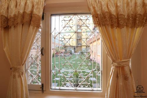a window with curtains and a view of a yard at Aarya Chaitya Inn in Kathmandu