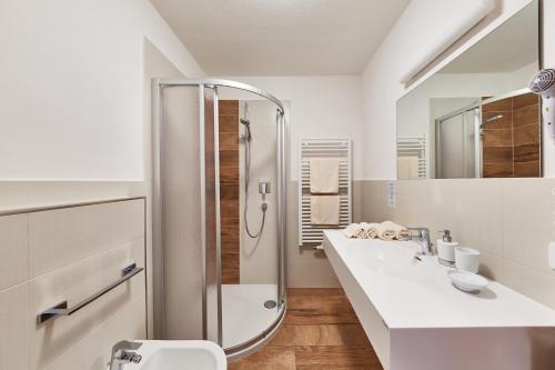 a white bathroom with two sinks and a shower at La Cianò in Corvara in Badia