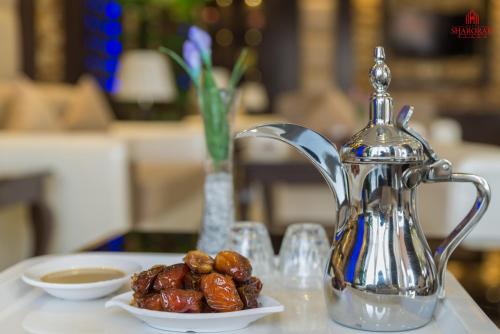 a silver tea kettle and bowls of dates on a table at فندق شروره بلازا الفندقية in Sharurah