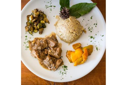a plate of food with meat and vegetables on a table at Rifugio Uschione in Chiavenna