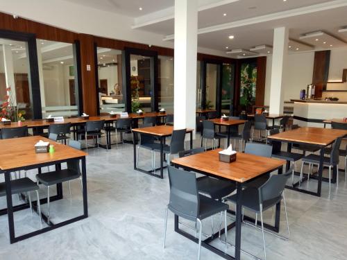 a restaurant with wooden tables and chairs and windows at Seventeen Hotel in Banda Aceh