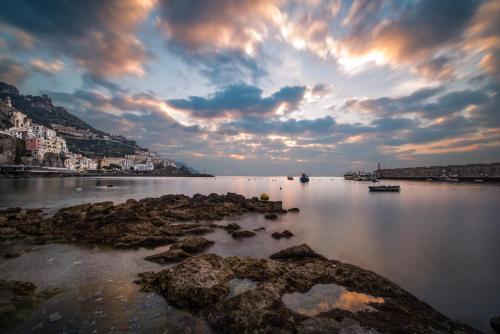 a large body of water with rocks and a cloudy sky at Vista d'Amalfi in Amalfi