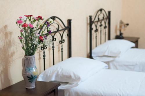un jarrón con flores en una mesa junto a dos camas en B&B L'Angelica, en Piazza Armerina