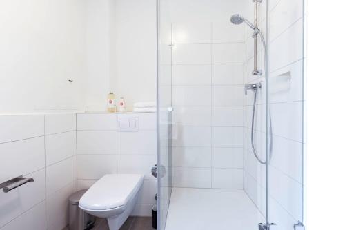uma casa de banho branca com um chuveiro e um WC. em Apartment St Johannis em Nuremberga