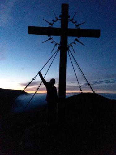 a man standing next to a cross on a hill at Die Nockalm in Turracher Hohe