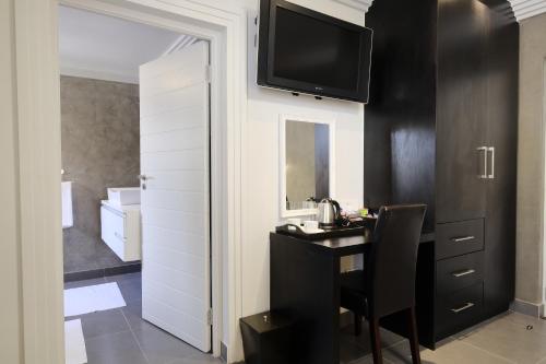 a room with a desk and a television on a wall at Villa Moyal in Johannesburg