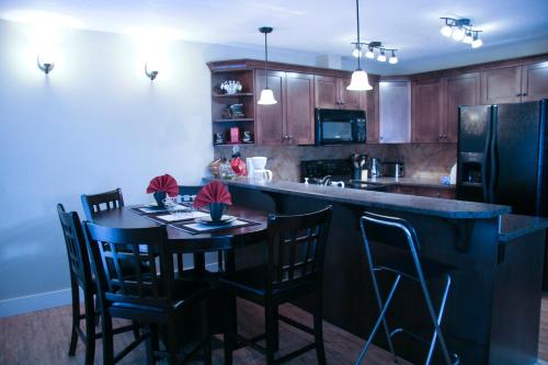 a kitchen with a bar and a table with chairs at Mountain View Radium Condo - Copper Horn Village in Radium Hot Springs