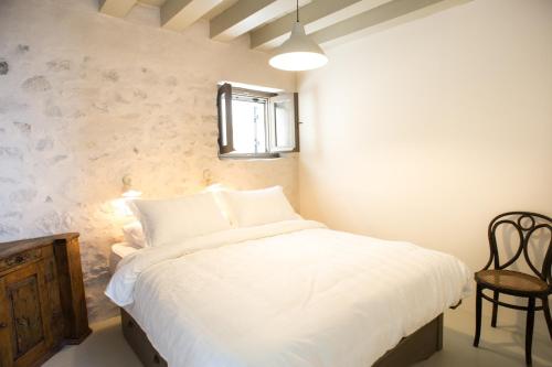 a bedroom with a bed with white sheets and a chair at Moustafa Stone House in Emporeiós