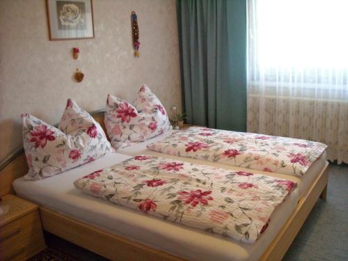 - une chambre avec 2 lits avec des draps floraux et une fenêtre dans l'établissement Ferienwohnung Zapfl Maria, à Greisdorf