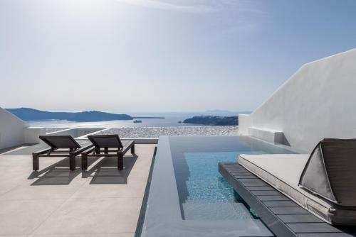 a pool on the roof of a house with two chairs at Cavo Tagoo Santorini in Imerovigli
