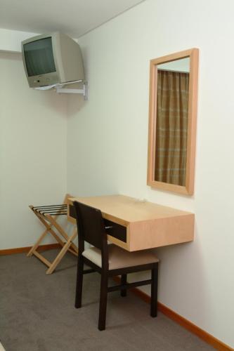 a room with a desk with a chair and a mirror at Hotel Recinto in Fátima
