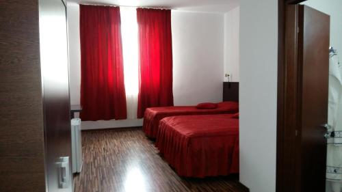 a room with two beds and a window with red curtains at Motel Cargo in Ţăndărei