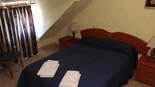 a bedroom with a blue bed with two towels on it at Hostal Aribel Longinos in Cercedilla
