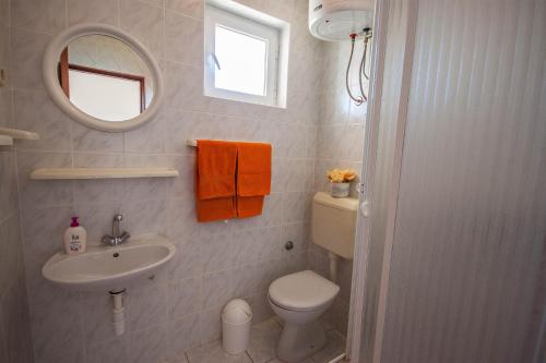 bagno con servizi igienici, lavandino e specchio di Apartments Bella Poljana a Ugljan (Ugliano)