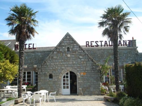 a restaurant with palm trees in front of a building at Ecume de Mer in Trébeurden