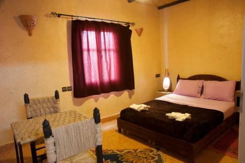 a bedroom with a bed and a red window at La Baraka Auberge in Aït Ben Haddou