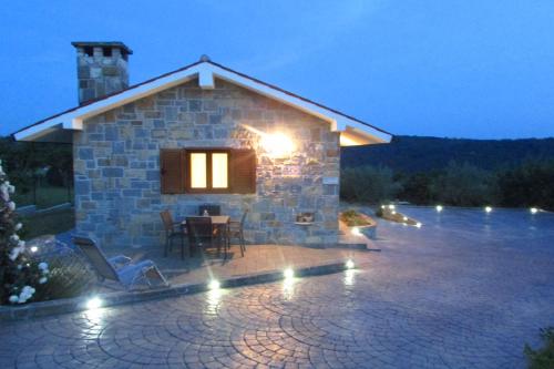 Casa de piedra con patio y mesa con luces en Holiday House Ida, en Marezige