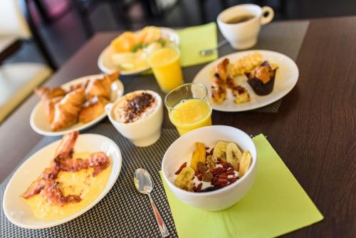 Una mesa cubierta con platos de desayuno y bebidas. en Hôtel Le Bayonne, en Bayona