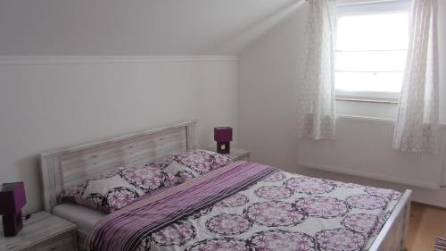 a bedroom with a bed with a purple bedspread and a window at Apartment Marin in Ogulin