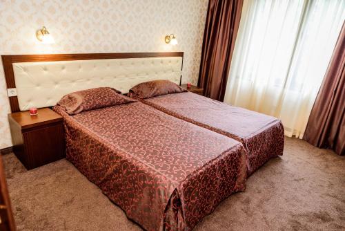 a bedroom with a bed with a red comforter at SPA Hotel Medicus in Varshets