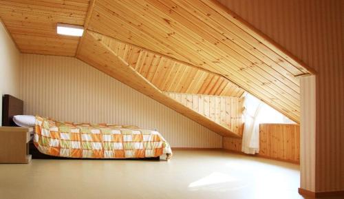 Zimmer im Dachgeschoss mit einem Bett und einer Holzdecke in der Unterkunft Eastern Park Pyeongchang in Pyeongchang