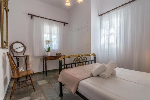 een slaapkamer met een bed, een stoel en een bureau bij Mandrakia Bliss House in Mandrakia