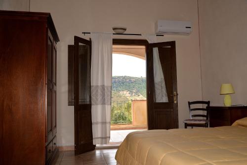 a bedroom with a bed and a sliding glass door at Hotel Valle del Cedrino in Galtellì
