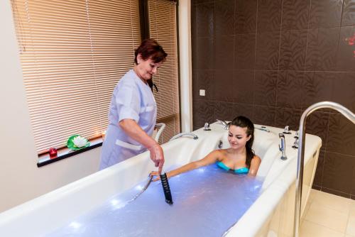 a man and a woman in a tub with a brush at SPA Hotel Medicus in Varshets