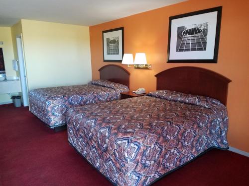 two beds in a hotel room with orange walls at Executive Inn in Panhandle