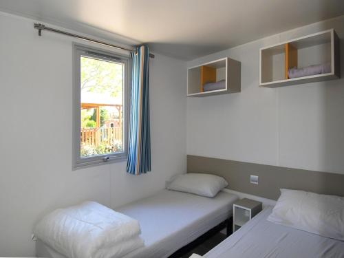 グリモーにあるVar Mobil Home, Les Prairies de la Merのベッド2台と窓が備わる客室です。