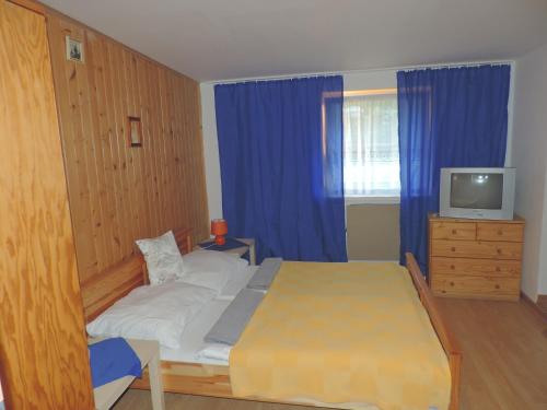a bedroom with a bed and a tv and blue curtains at Western Penzion in Ružomberok