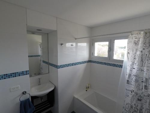 a white bathroom with a sink and a bath tub at Ayres del Sur in Puerto Madryn