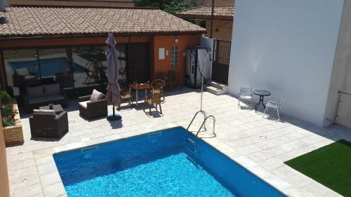a swimming pool and a patio with a table and chairs at Apartamentos de turismo rural Las Eras in Castelserás