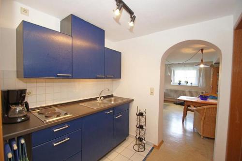 a kitchen with blue cabinets and a kitchen table at Haus Pollak in Waldkirchen