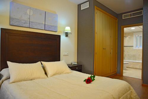 a bedroom with a bed with a flower on it at Hotel & Spa PLAZA Arriate in Arriate