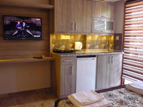 a kitchen with wooden cabinets and a tv on the wall at Street61 Apart Hotel in Sarigerme