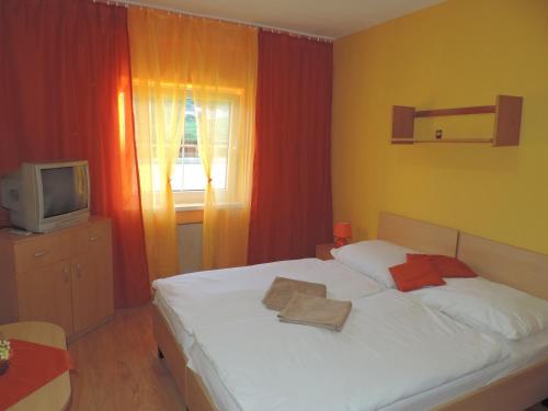 a bedroom with a white bed and a television at Western Penzion in Ružomberok