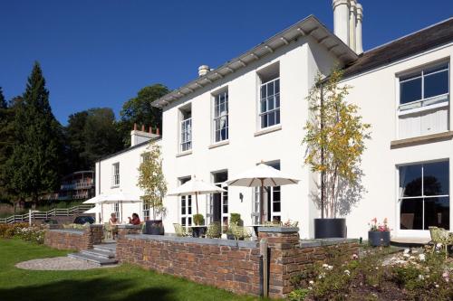 a white house with umbrellas in the yard at The Cornwall Hotel Spa & Lodges in St Austell