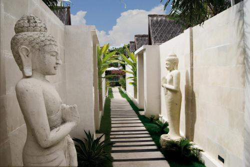 two white statues standing next to a wall at Kaleydo Villas in Gili Trawangan