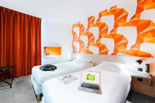 a room with two beds with a laptop on top of them at The Originals City, Ara Hôtel, Landerneau in Landerneau