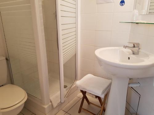 a bathroom with a sink and a shower and a toilet at Hôtel Des Poètes avec parking sur réservation in Béziers