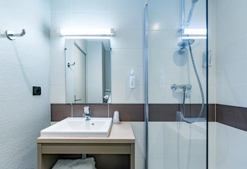 uma casa de banho com um lavatório e um chuveiro em The Originals City, Ara Hôtel, Landerneau em Landerneau