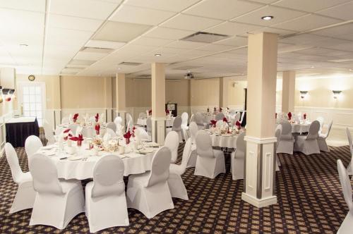 a banquet hall with white tables and white chairs at L'Escale Hôtel Suites in Val-dʼOr