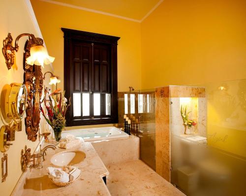 a bathroom with a tub and a sink and a bath tub at Casa Azul Monumento Historico in Mérida