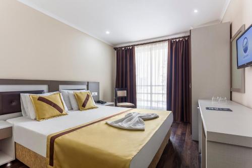 Habitación de hotel con cama grande y escritorio. en Ayhan Hotel en Antalya