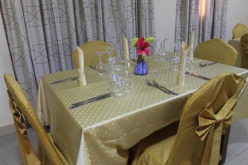 a table with a yellow table cloth and a table with chairs at Hotel Novela Star in Lomé